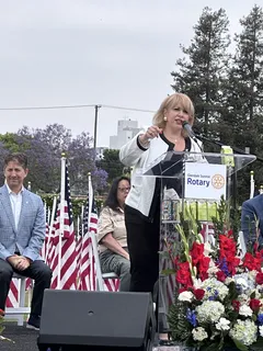 Melina Sardar speaking at an outdoor community event